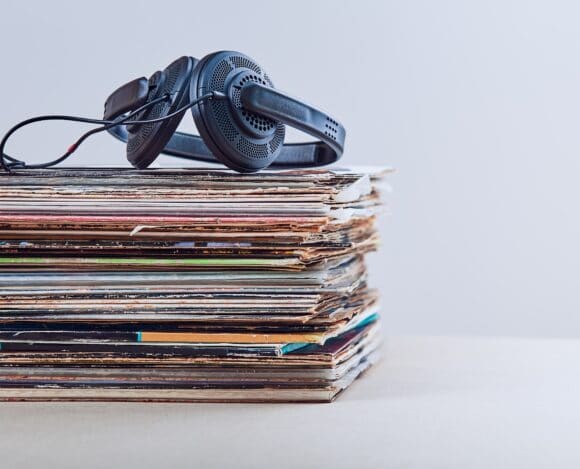 Stack of many black vinyl recordss, headphones put on the top of vinyls. Copy space for text. Candid people, real moments, authentic situations